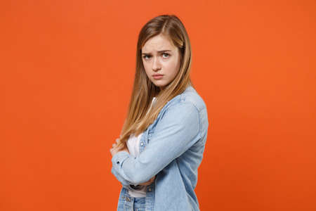 Side view of dissatisfied young woman girl in casual denim clothes posing isolated on orange background in studio.の写真素材