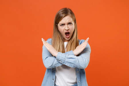 Irritated young woman girl in casual denim clothes posing isolated on orange wall background.の写真素材