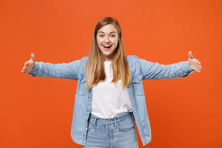 Excited young woman girl in casual denim clothes posing isolated on orange background in studio.の写真素材