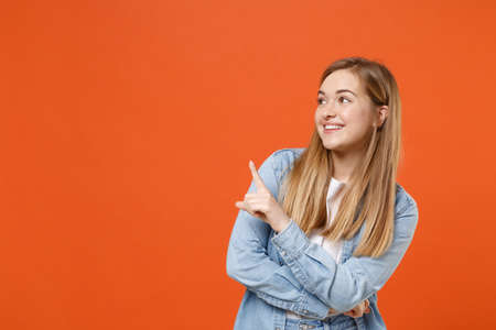 Pretty young woman girl in casual denim clothes posing isolated on orange background studio portrait.の写真素材