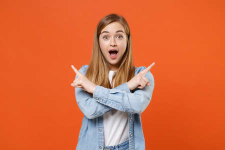 Shocked young woman girl in casual denim clothes posing isolated on orange background studio portraitの写真素材