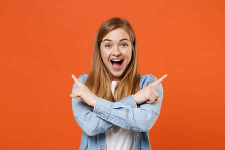 Excited young woman girl in casual denim clothes posing isolated on orange background studio portrait.の写真素材