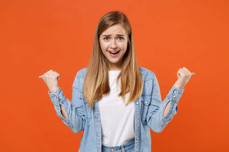 Smirked excited young woman girl in casual denim clothes posing isolated on orange background studio portrait.の写真素材