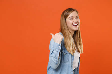 Side view of laughing young woman girl in casual denim clothes posing isolated on orange background studio portrait.の写真素材