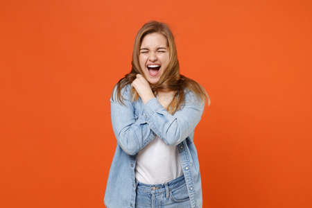 Screaming young woman girl in casual denim clothes posing isolated on orange background studio...