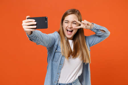 Cheerful young woman girl in casual denim clothes posing isolated on orange background in studio.の写真素材