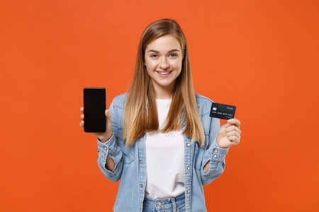 Smiling young woman girl in casual denim clothes posing isolated on orange wall background.の写真素材