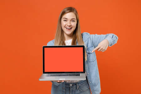 Cheerful young woman girl in casual denim clothes posing isolated on orange background.の写真素材