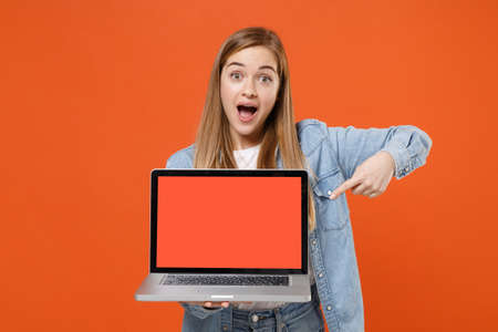 Shocked young woman girl in casual denim clothes posing isolated on orange background.の写真素材