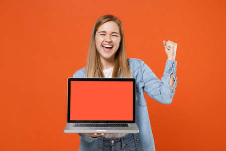 Happy young woman girl in casual denim clothes posing isolated on orange background.の写真素材