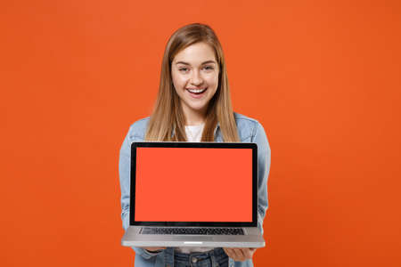 Cheerful young woman girl in casual denim clothes posing isolated on orange background studio portrait.の写真素材