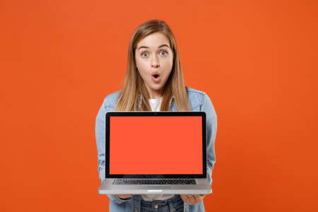 Shocked young woman girl in casual denim clothes posing isolated on orange background studio portrait.の写真素材