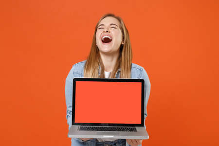 Laughing young woman girl in casual denim clothes posing isolated on orange background studio portrait.の写真素材