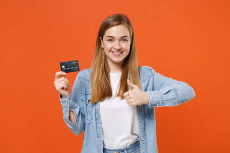 Smiling young woman girl in casual denim clothes posing isolated on bright orange background studio portrait.の写真素材