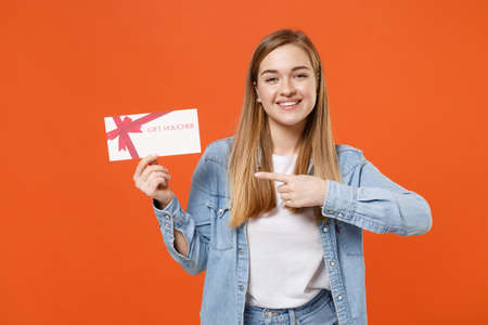 Smiling young woman girl in casual denim clothes posing isolated on orange background studio portrait.の写真素材