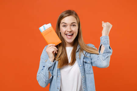 Joyful young woman girl in casual denim clothes posing isolated on orange background in studio.の写真素材