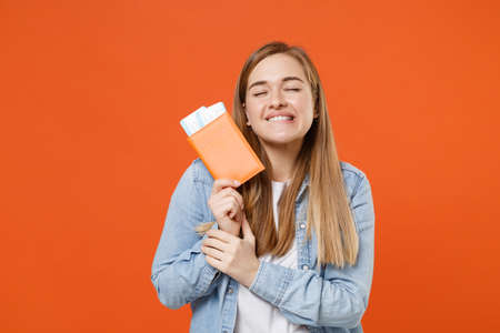 Pensive young woman girl in denim clothes posing isolated on orange background studio.の写真素材
