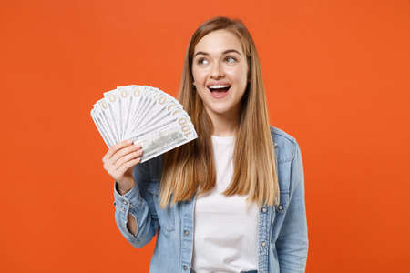 Excited young woman girl in casual denim clothes posing isolated on orange wall background studio portrait.の写真素材