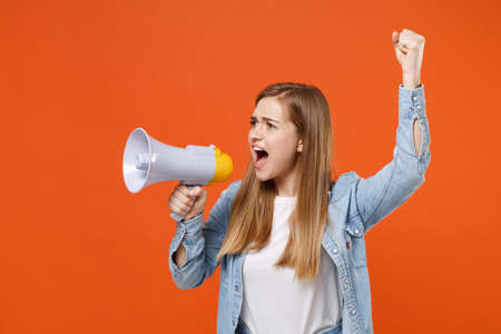 Shocked young woman girl in casual denim clothes posing isolated on orange background studio portrait.の写真素材