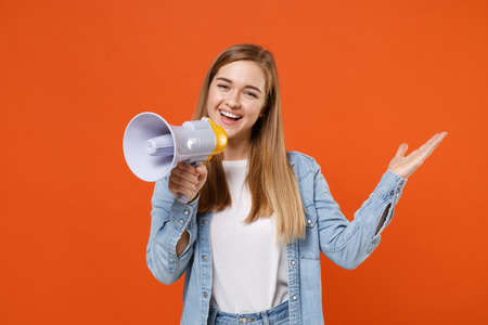 Cheerful young woman girl in casual denim clothes posing isolated on orange wall background studio portrait.の写真素材