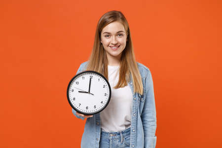 Smiling beautiful young woman girl in casual denim clothes isolated on bright orange wall background studio portrait.の写真素材
