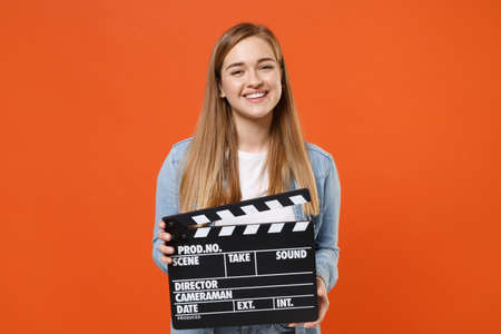 Smiling young woman girl in casual denim clothes posing isolated on orange wall background studio portrait.の写真素材