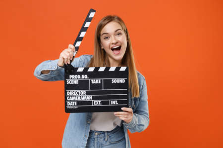 Excited young woman girl in casual denim clothes posing isolated on orange wall background studio portrait.の写真素材