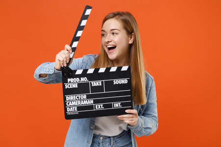 Cheerful young woman girl in casual denim clothes posing isolated on orange wall background studio portrait.の写真素材