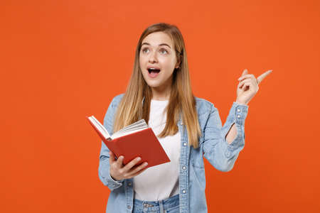 Excited young woman girl in casual denim clothes posing isolated on orange background studio portrait.の写真素材