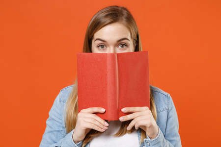 Pretty young woman girl in casual denim clothes posing isolated on bright orange background studio portrait.の写真素材