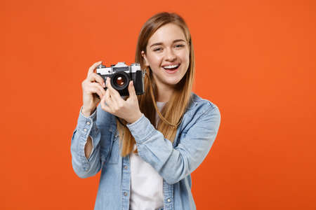 Cheerful young woman girl in casual denim clothes posing isolated on orange background studio portrait.の写真素材