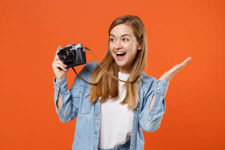 Excited young woman girl in casual denim clothes posing isolated on orange background studio portrait.の写真素材