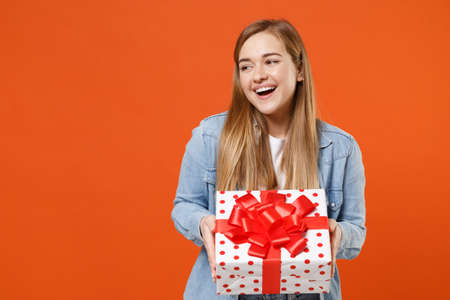 Cheerful young woman girl in casual denim clothes isolated on orange wall background.の写真素材