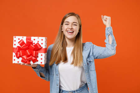 Joyful young woman girl in casual denim clothes isolated on orange background.の写真素材