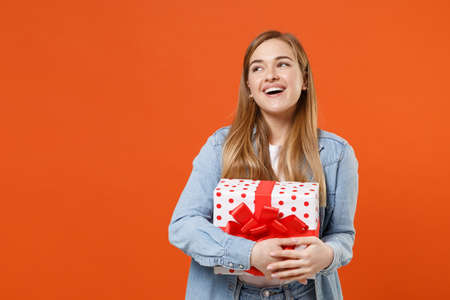 Funny pensive young woman girl in casual denim clothes isolated on orange background.の写真素材
