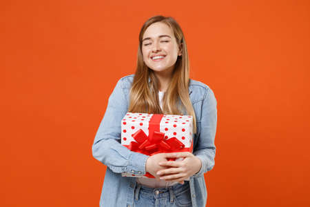 Smiling pensive young woman in casual denim clothes isolated on orange background.の写真素材