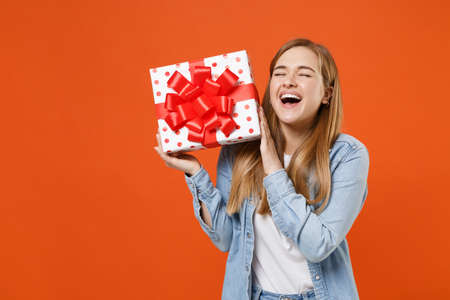 Cheerful funny young woman in casual denim clothes isolated on orange background.の写真素材