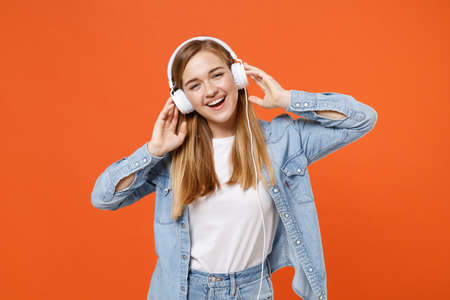 Cheerful young woman girl in casual denim clothes posing isolated on orange background studio portrait.の写真素材