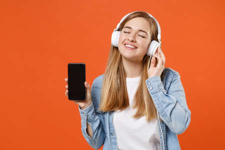 Smiling woman in denim clothes isolated on orange background. People lifestyle concept.の写真素材