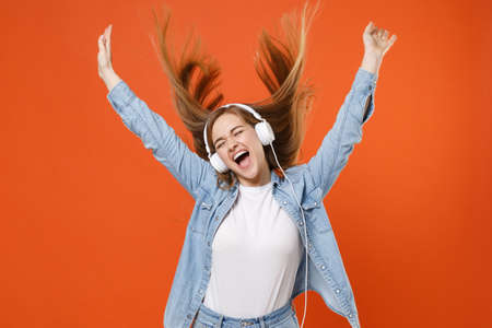 Crazy young woman girl in casual denim clothes posing isolated on orange background. People lifestyle concept.の写真素材