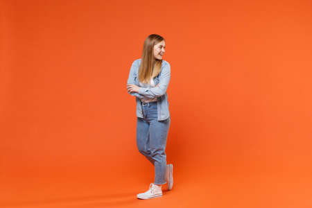 Side view of cheerful young woman girl in casual denim clothes posing isolated on orange background studio portrait.の写真素材