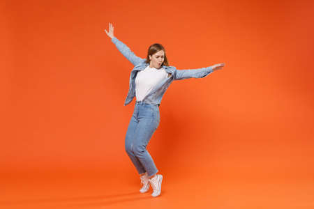 Funny young woman girl in casual denim clothes posing isolated on orange background studio portrait.の写真素材