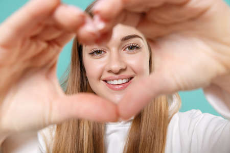 Smiling young woman girl in casual white hoodie posing isolated on blue turquoise background in studio.の写真素材