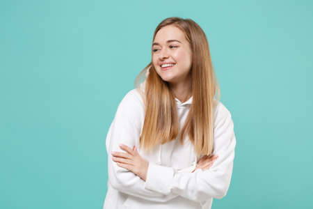 Smiling young woman girl in casual white hoodie posing isolated on blue turquoise wall background studio portrait.の写真素材
