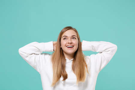 Pretty young woman girl in casual white hoodie posing isolated on blue turquoise background studio portrait.の写真素材