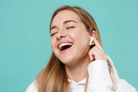 Funny young woman in casual white hoodie posing isolated on blue turquoise background studio...