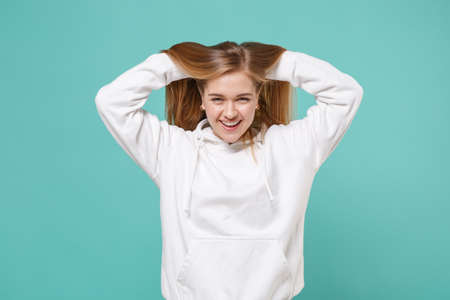 Stunning smiling young woman girl in casual white hoodie posing isolated on blue turquoise background studio portrait.の写真素材