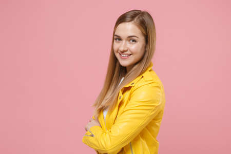 Side view of smiling young woman girl in yellow leather jacket posing isolated on pastel pink...