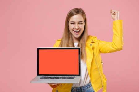 Happy young woman girl in yellow leather jacket isolated on pastel pink background.の写真素材
