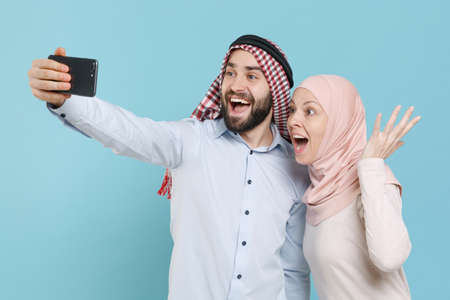 Amazed couple friends arabian muslim man wonam in keffiyeh kafiya ring igal agal hijab clothes isolated on blue background.の写真素材